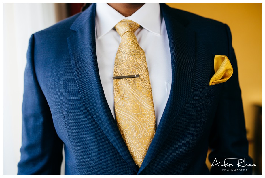 gold colored tie and navy suit